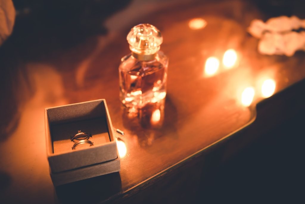 Perfume near box with ring on table